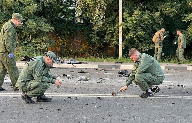 In this photo taken from video released by Russia's Investigative Committee on Sunday, Aug. 21, 2022, investigators work at the scene of the explosion of a car driven by Daria Dugina outside Moscow.