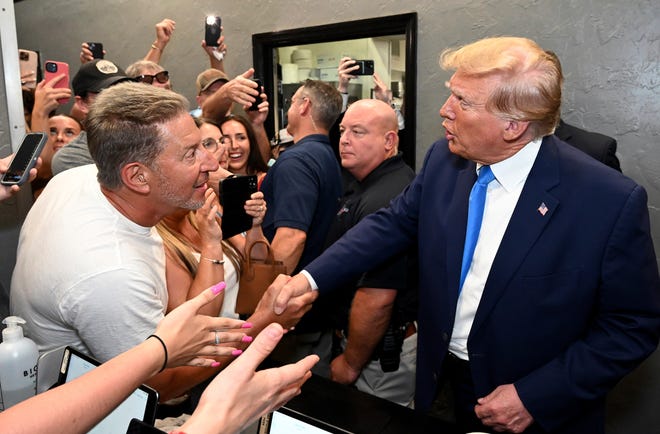 Former President Donald Trump stops by the Downtown House of Pizza as he greets supporters after delivering a speech at the Lee County Republican Dinner in Fort Myers.  Trump also criticized Gov. Ron DeSantis in that address.