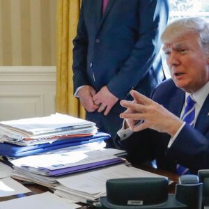 Then-President Donald Trump sits at his desk after a meeting with Intel CEO Brian Krzanich in the Oval Office of the White House in Washington, Feb. 8, 2017, as a lockbag is visible on the desk, the key still inside at left. (AP Photo/Pablo Martinez Monsivais)