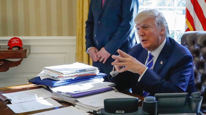 Then-President Donald Trump sits at his desk after a meeting with Intel CEO Brian Krzanich in the Oval Office of the White House in Washington, Feb. 8, 2017, as a lockbag is visible on the desk, the key still inside at left. (AP Photo/Pablo Martinez Monsivais)